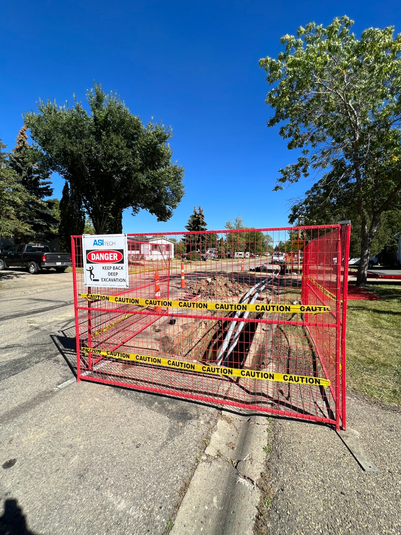Deep excavation with conduit installation behind safety fencing