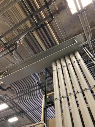 Overhead conduit bank routing through industrial facility ceiling